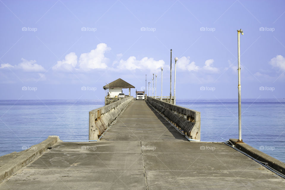 Cars on the concrete bridge pier fishing in the sea and the bright sky