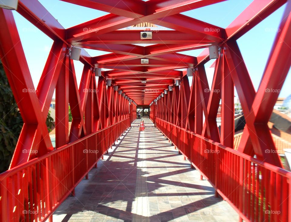 Ponte metálica vermelha com sol forte projetando sombra.
Puente metálico rojo con sol fuerte proyectando sombra.
Red metallic bridge with strong sun casting shadow.