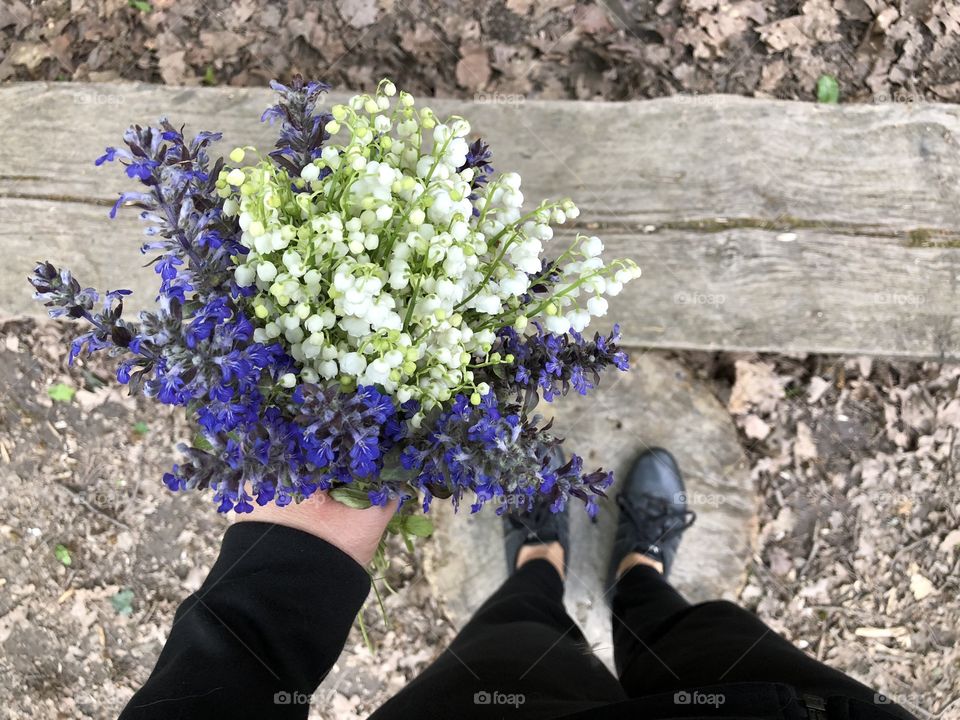 Woman’s hand holding a lily of the valley bouquet with blue flowers