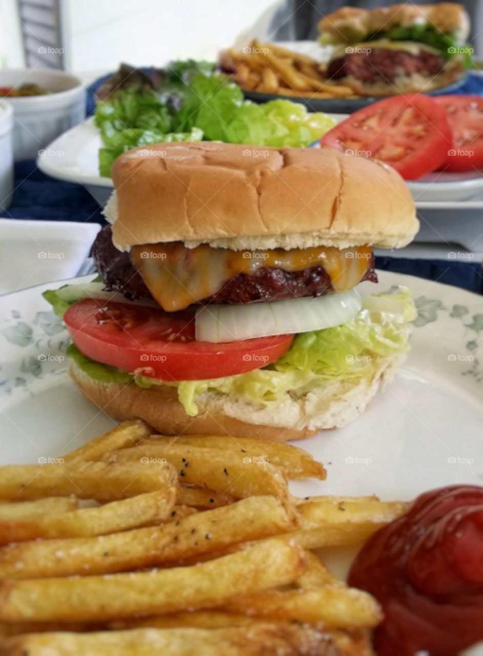 Hamburger with cheese onion tomato lettuce french fries ketchup