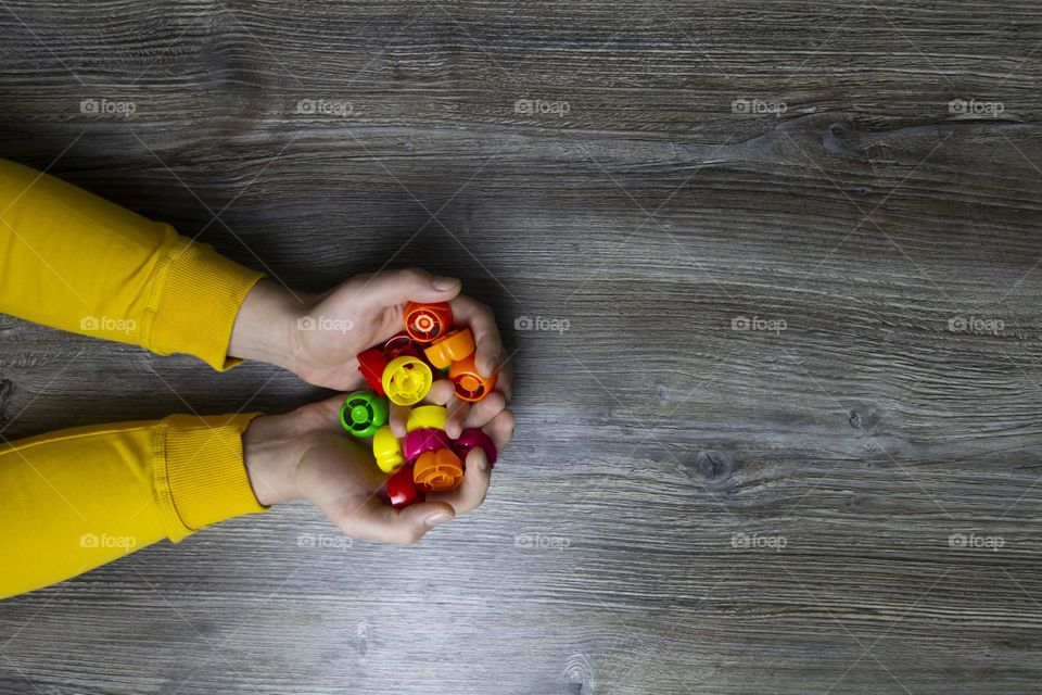 We collect garbage, plastic plugs and plastic to save our planet, nature and the environment. Men's hands lie on a gray wooden surface, which is used as a background or a surface with incident light.