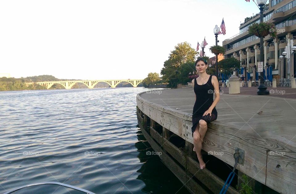 Women on side of wooden dock by water and bridge Georgetown DC