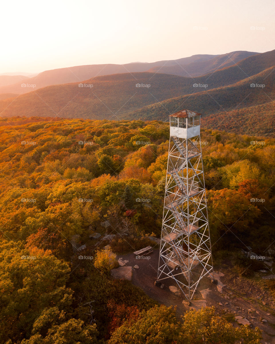 Mountain fire tower surrounded by fall foliage during a gorgeous warm sunset. 