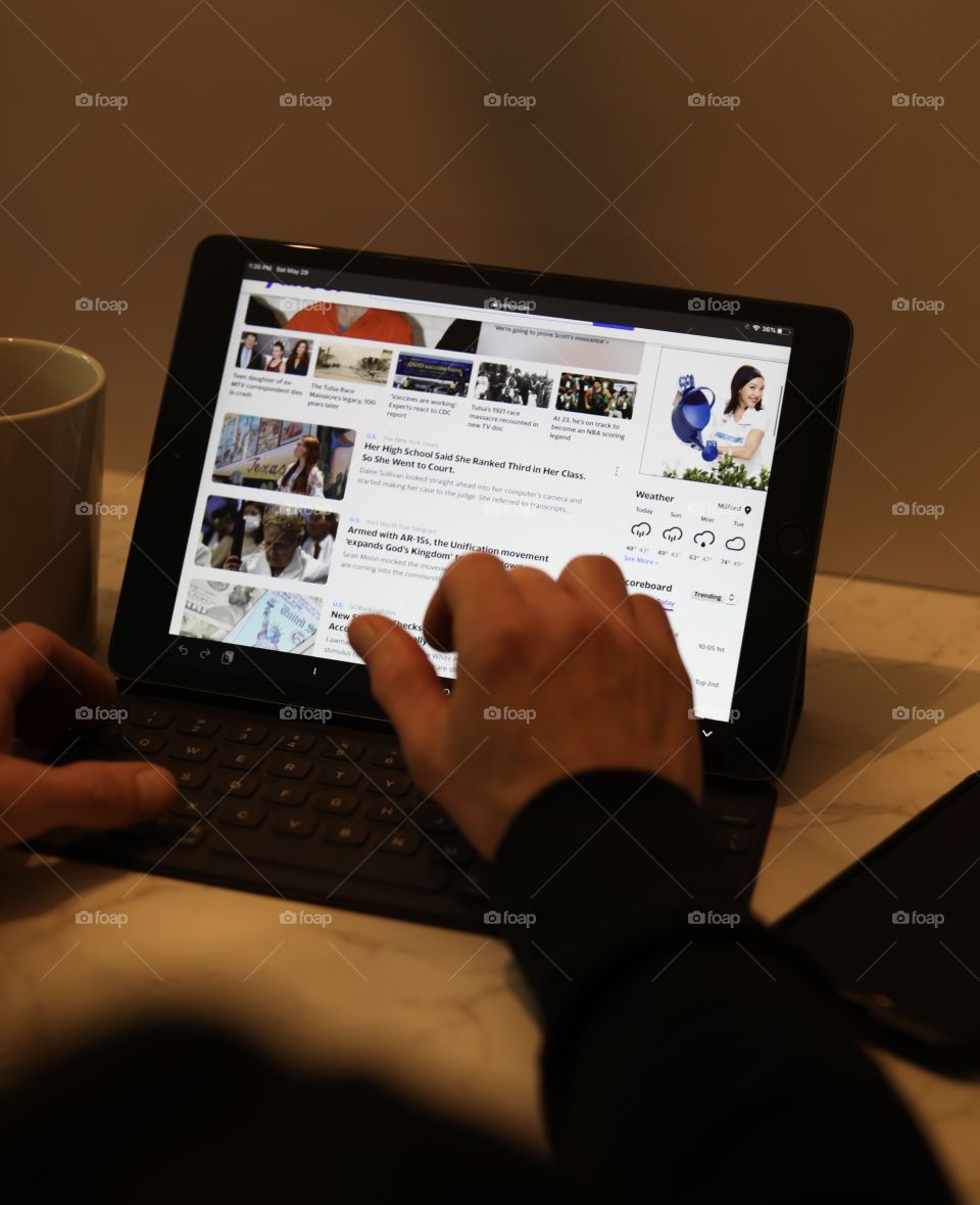 Man using search engine on Gen 7 iPad with coffee and iPhone 11 Pro Max