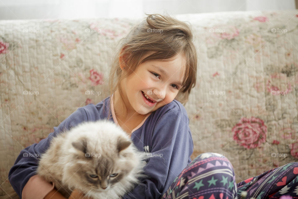 Little girl in pajamas with white cat