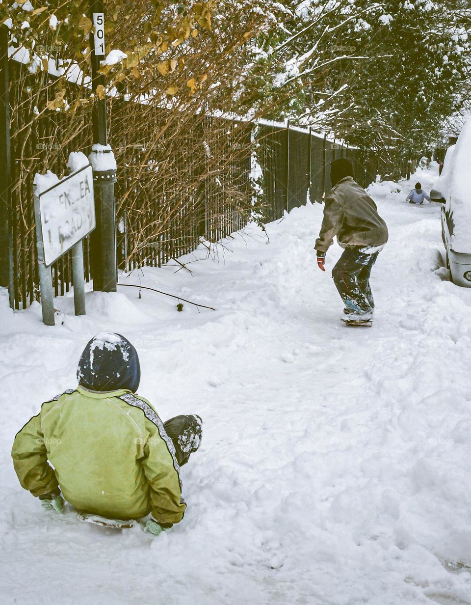 Kids sliding down a snowy residential street