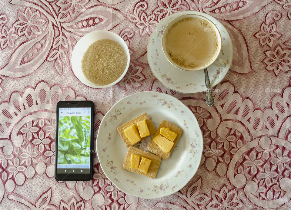 A Layout Of A Cup Of Hot Coffee, Sugar, Biscuit And Cheese And A Mobile Phone