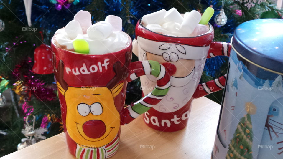 festive hot chocolates in Christmas mugs by the Christmas tree