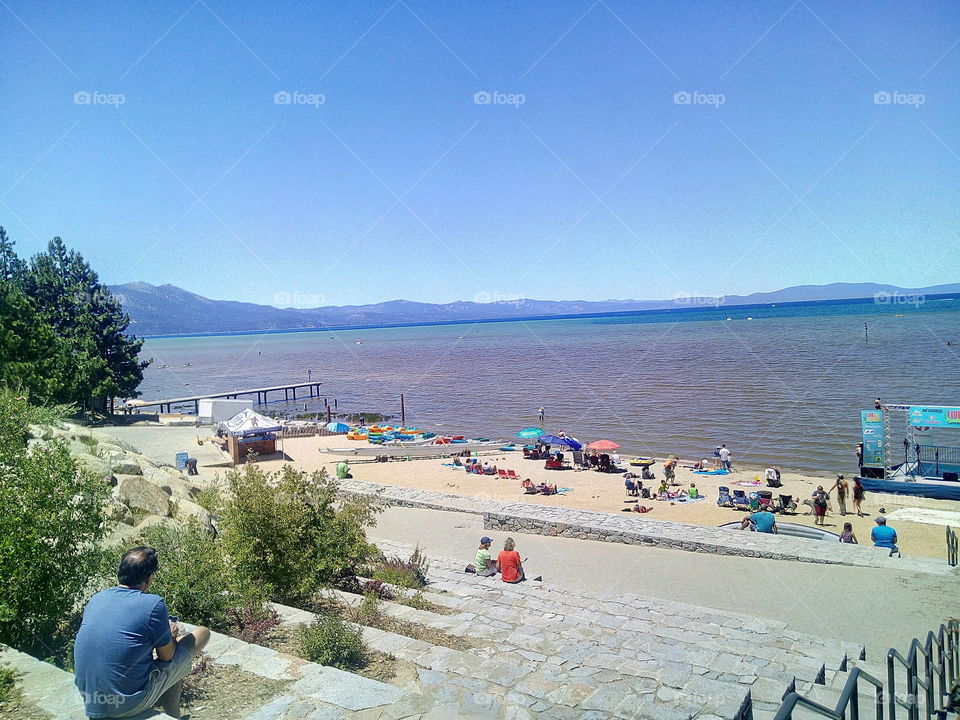 South Lake Tahoe beach, Pact with people soaking up the California sun with a beautiful mountain view up ahead.
