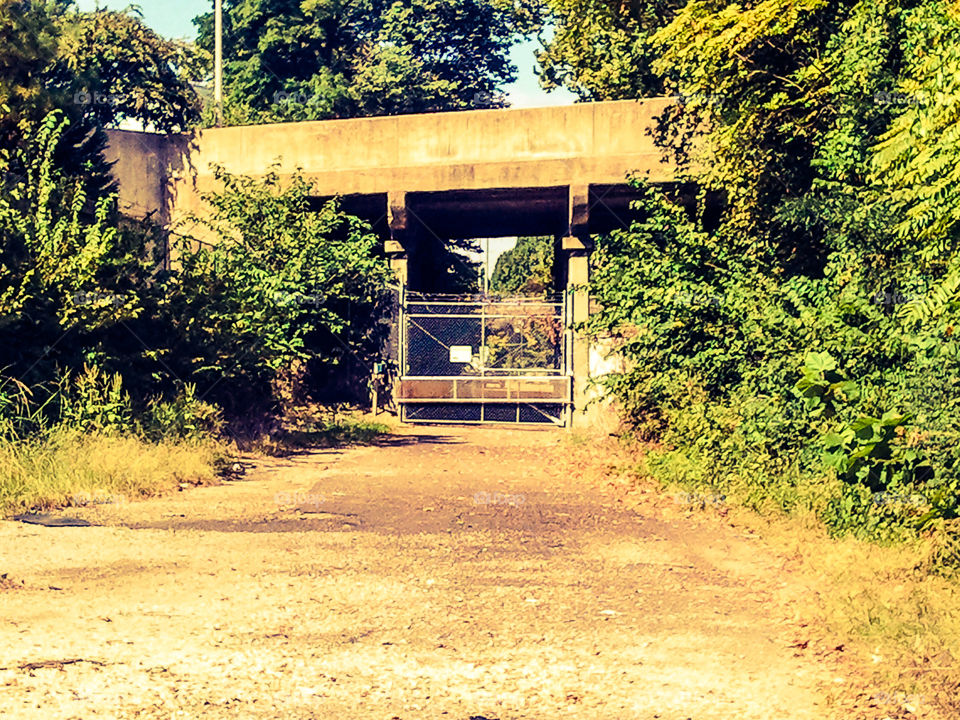 Sunset Mystery. A gated off path under a bridge.