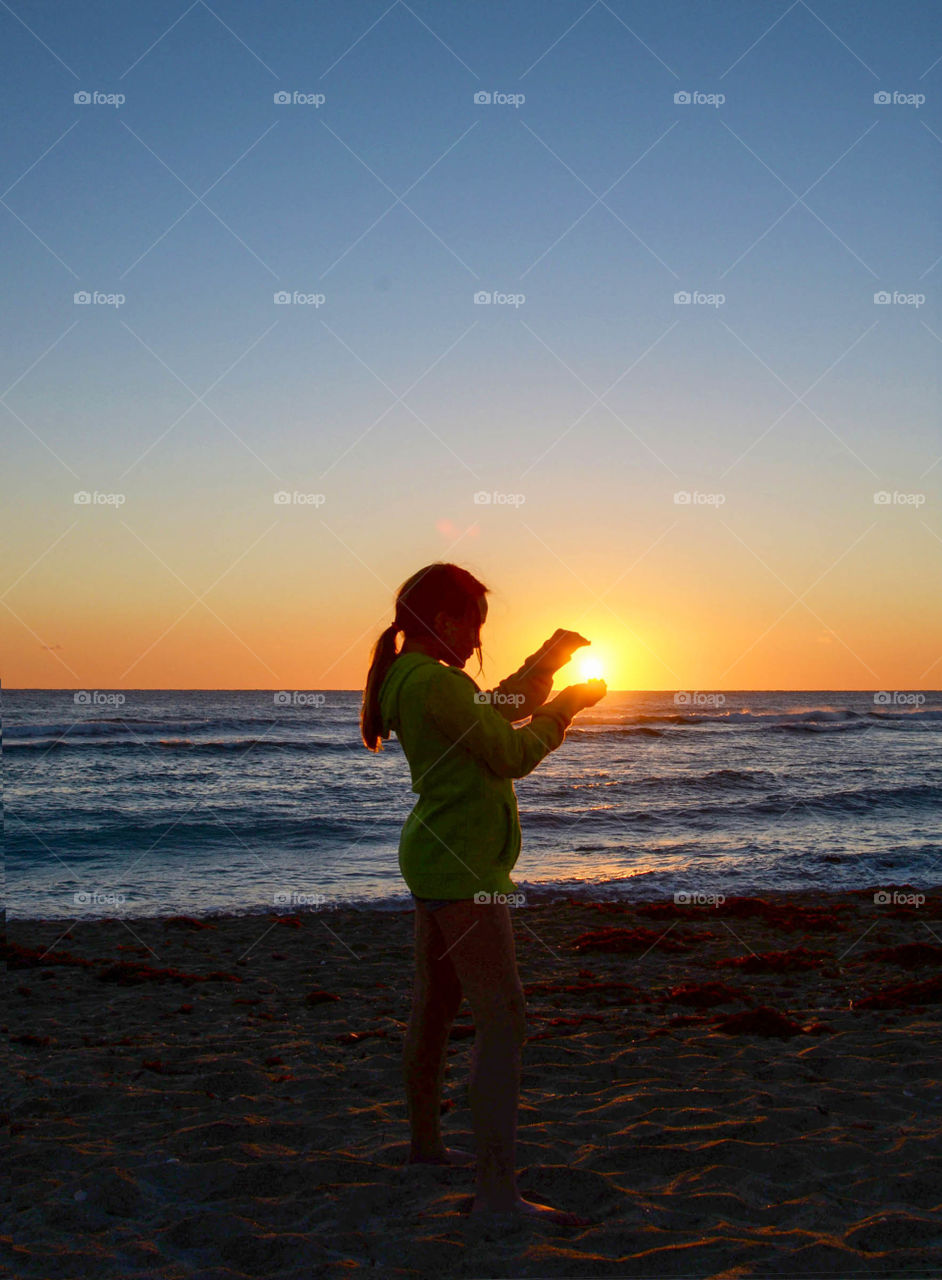 Catching the sunrise. Little girl literally holding the sun in her hands