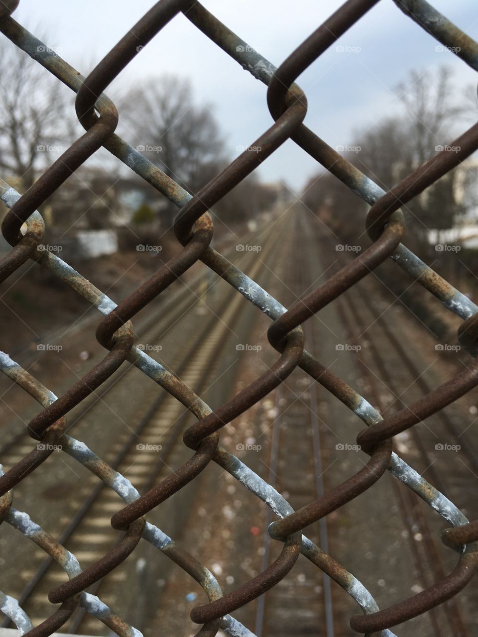 Railroad tracks seen through a chain link fence