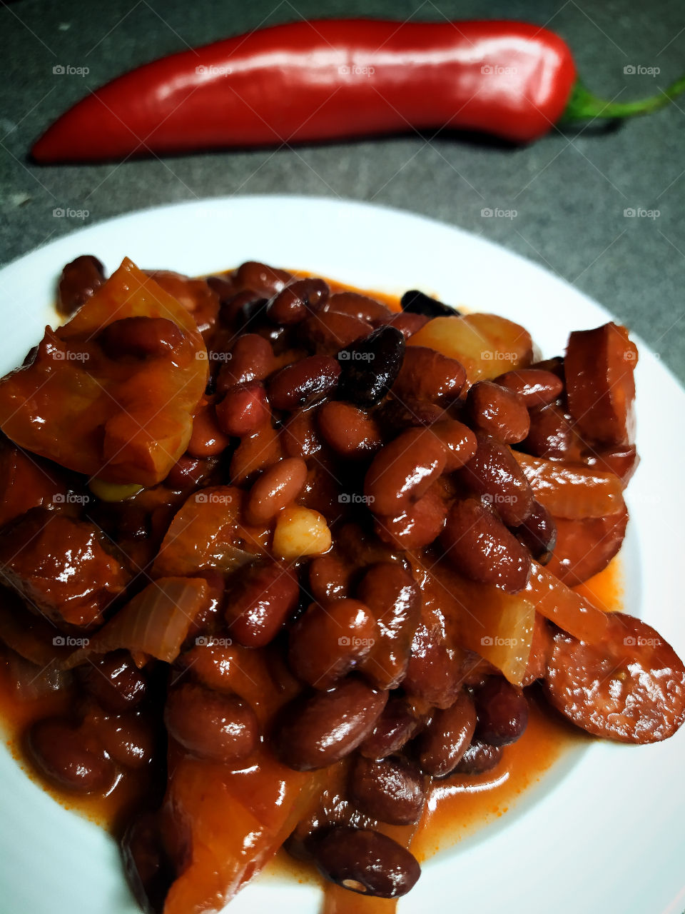 Plate with stewed beans in vegetables and chili pepper