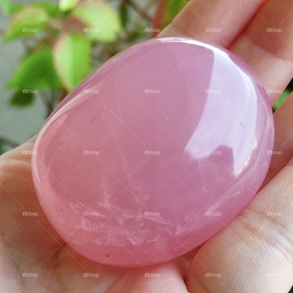 A polished rose quartz crystal palm stone.