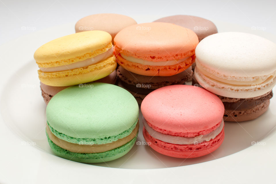 Colorful french macarons on a plate isolated in white background.