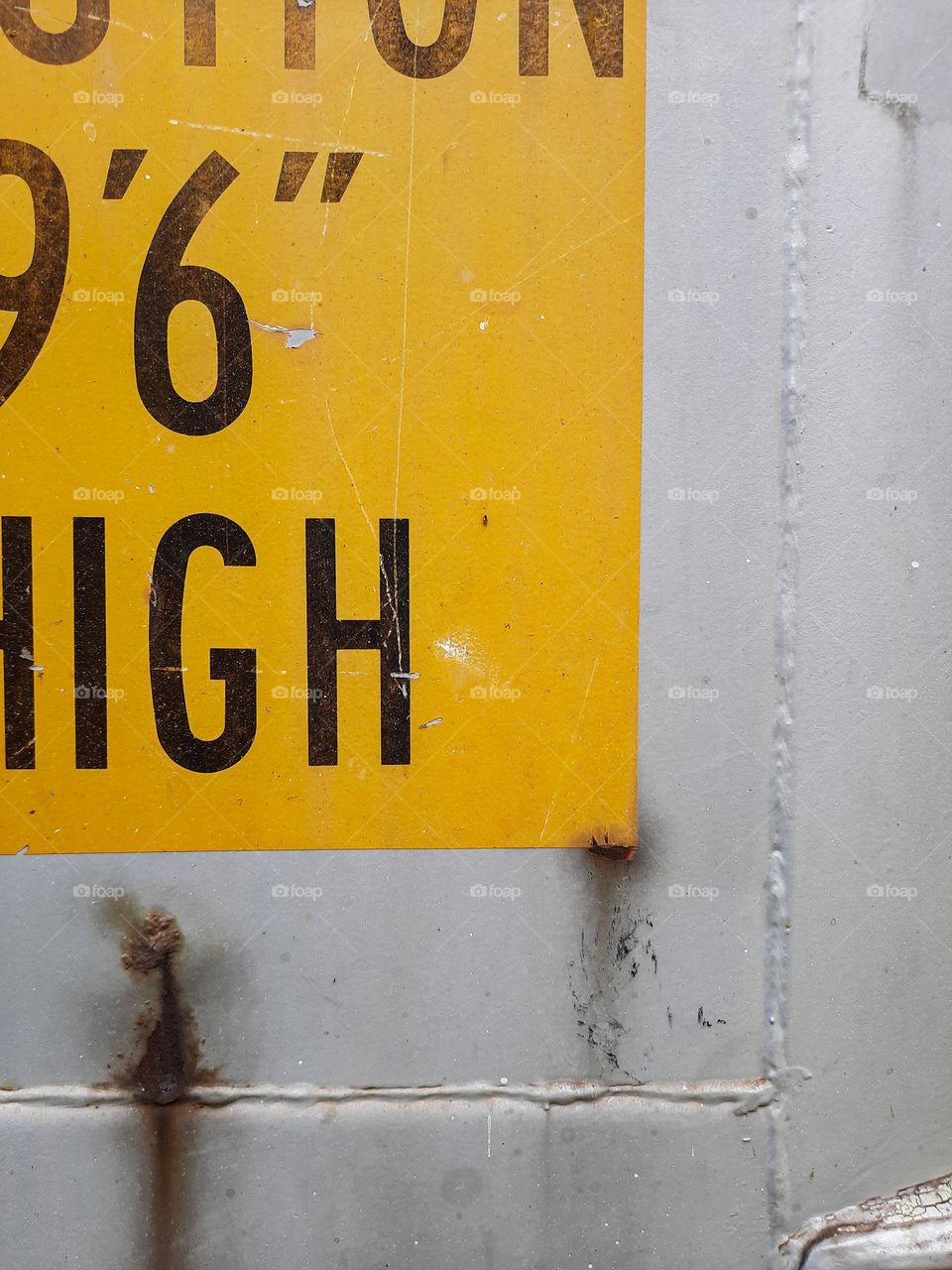 In grey and yellow. Yellow warning sign on grey painted shipping container.