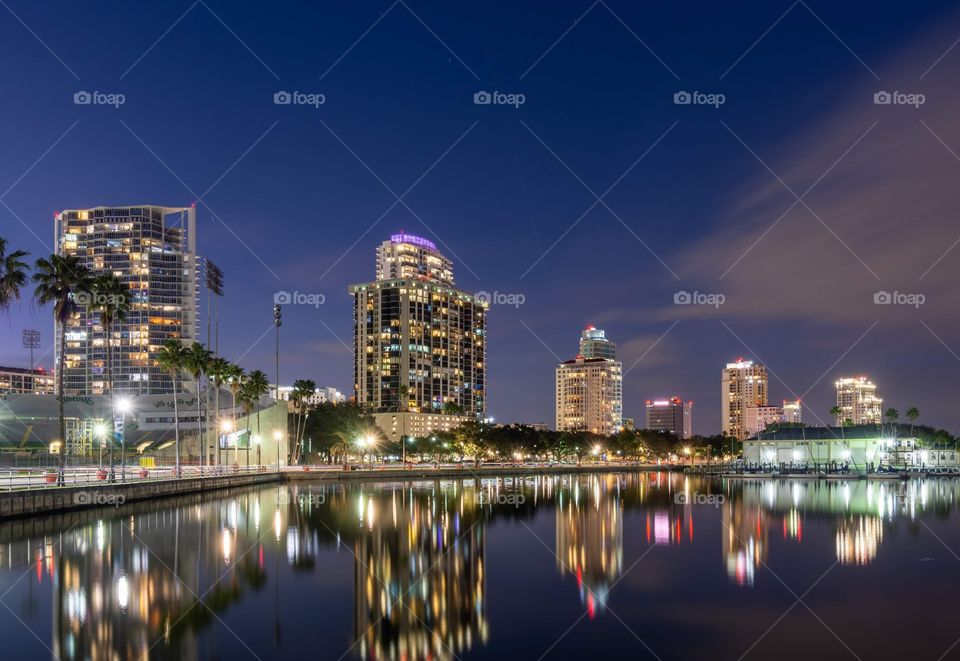 sparkling lights on tall buildings of St. Petersburg Florida skyline against a deep blue night sky and reflected in the water