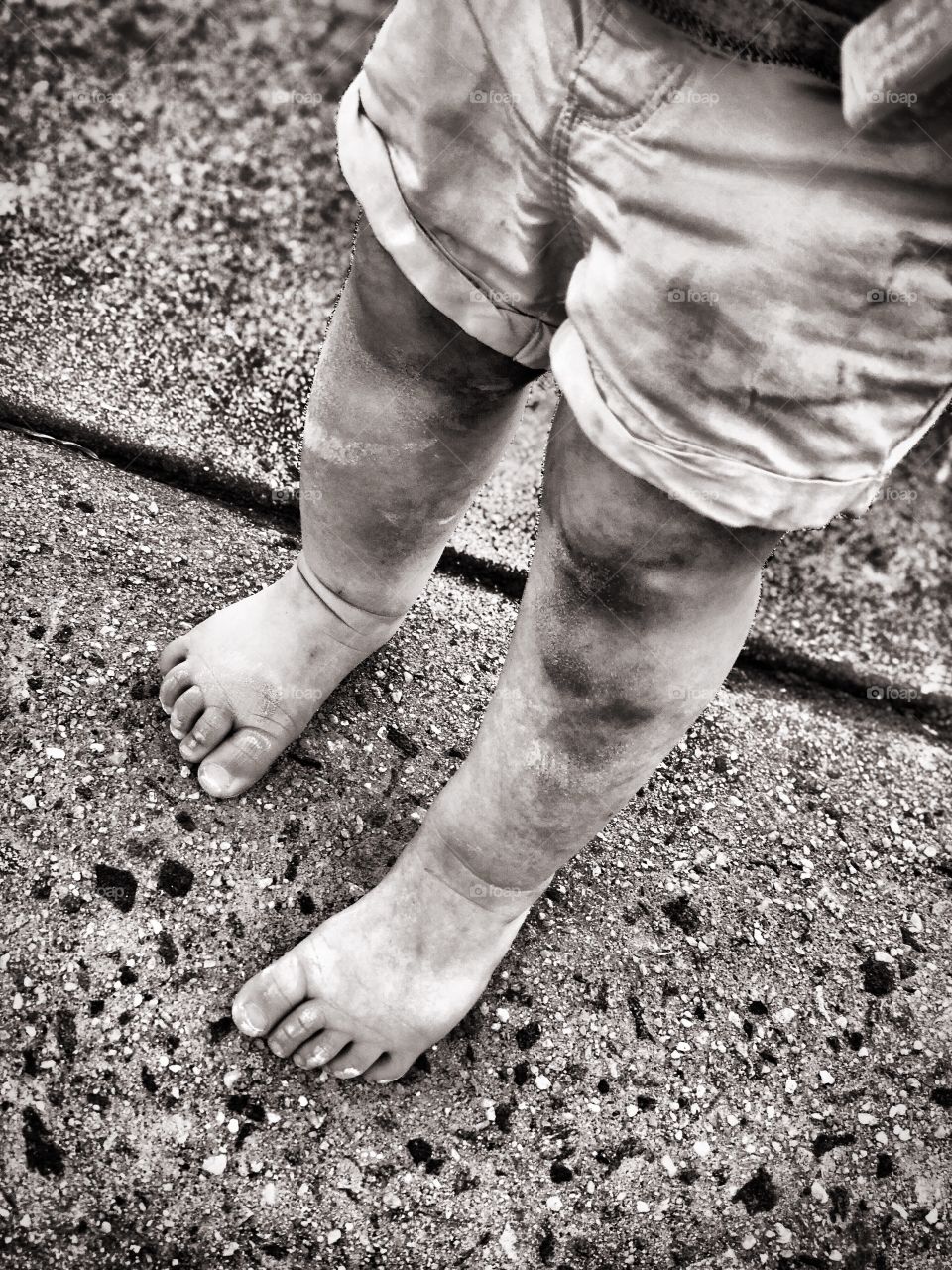 Toddlers feet, dirty with sidewalk chalk while coloring the driveway outside, in Black and White