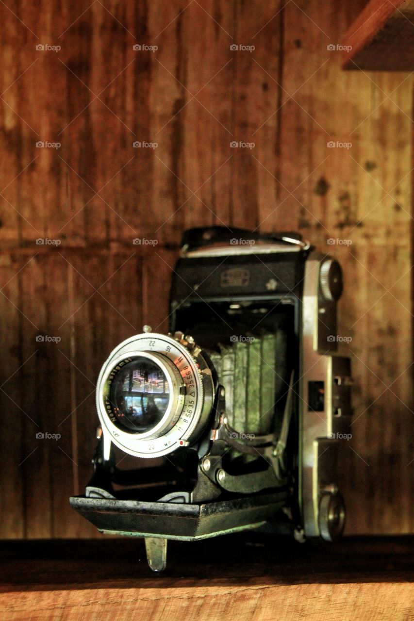 A classic black old camera is beautifully displayed on a shelf.