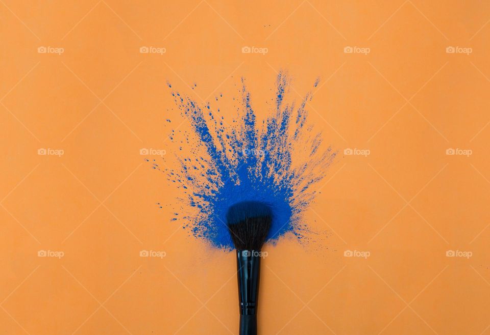 Color clash - make up, brush, blue powder on orange background
