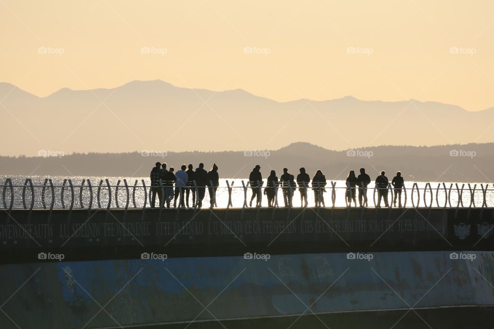 People on the breakwater on sunset