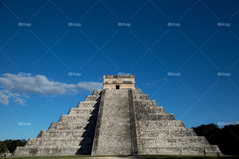 A man kneels to photograph his wife at Chichen Itza 