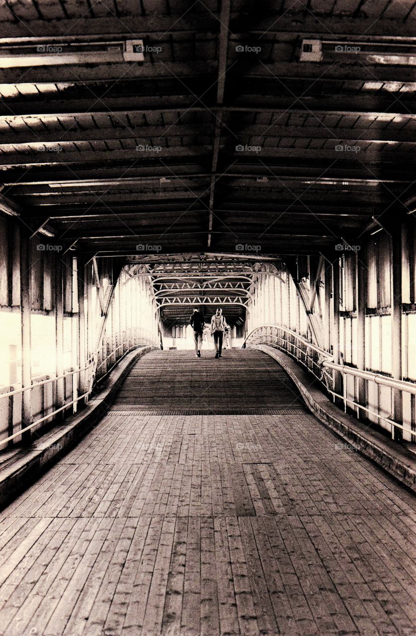 Two people walking on bridge