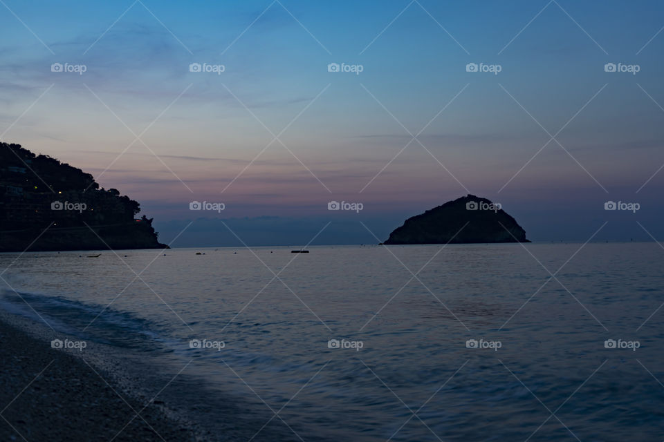Sunrise over the sea. The sun rises from behind the peninsula and passes from the islet next to it.
Wonderful colors are created, including purple, red, orange, blue.