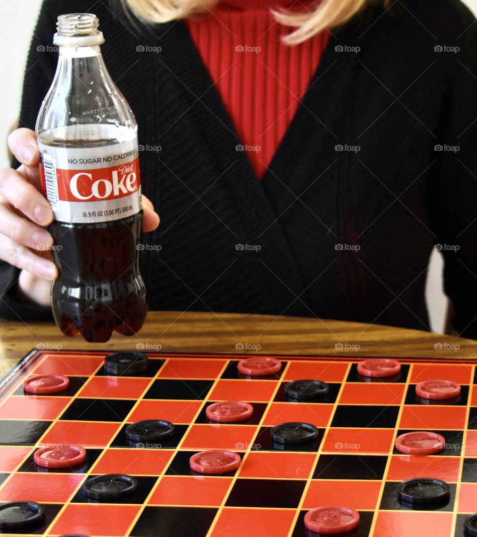 Woman drinking Diet Coke and playing checkers 