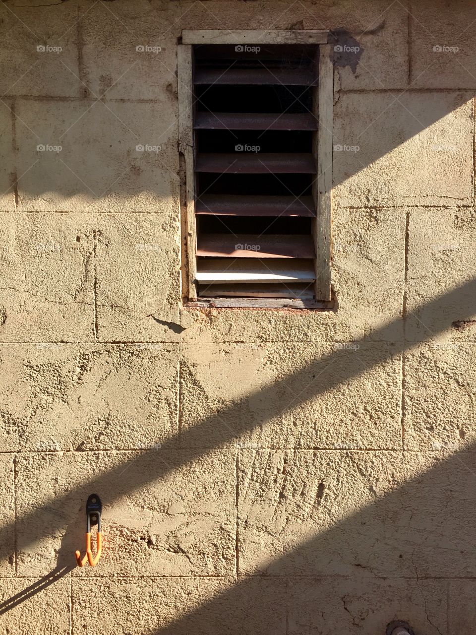 Old vented wood frame window in run down cinder block structure minimalist 