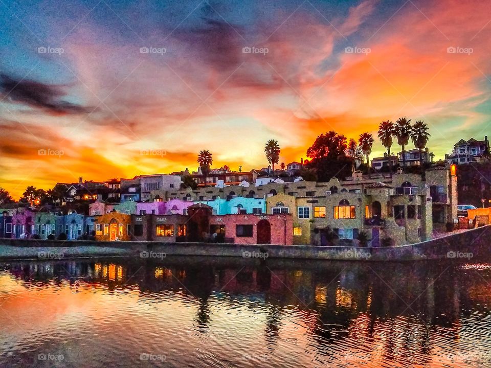 A beautiful sunset in Capitola California on the beach with the famous colorful Venetian condominiums with the reflection of the stunningly vibrant dusk sky on the Soquel River on the Monterey Bay