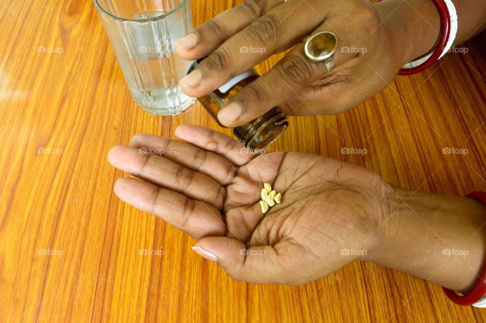 Self-treatment at home as per prescribed by doctor. Close up of a woman pouring medicine into her hand. Medical, health care or people concept. High Angel view. Close up with copy space room for text.