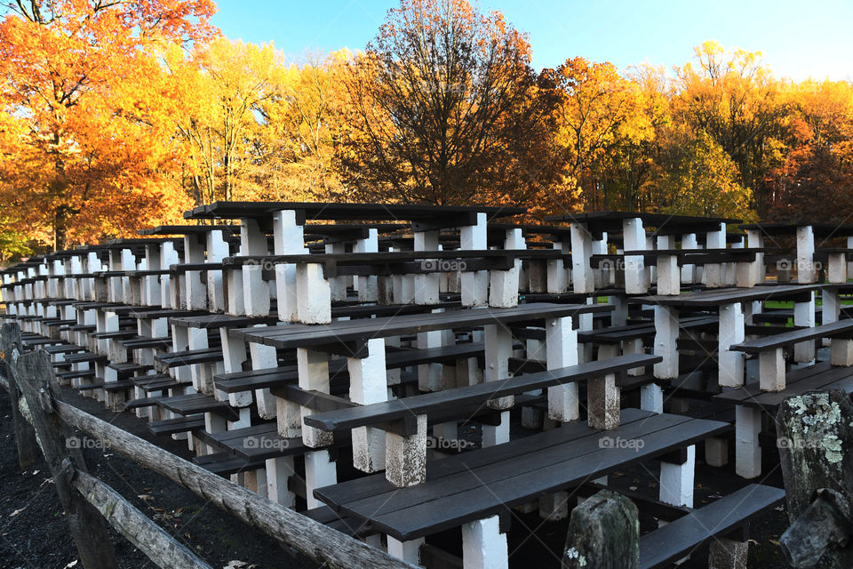 Stacked up park picnic tables put away for the change of season give way to beautiful fall foliage.