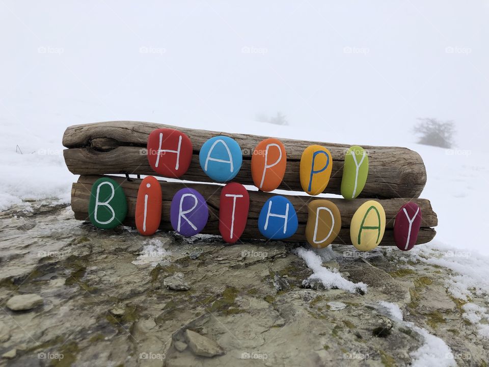 Happy Birthday, creative stones composition with snow background