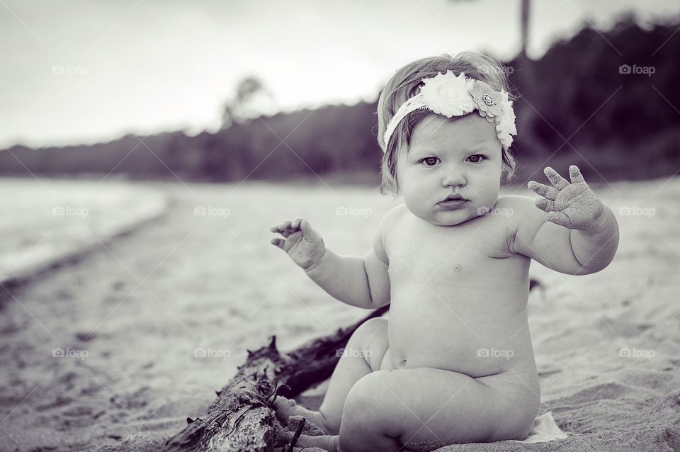Portrait of cute baby girl sitting on beach