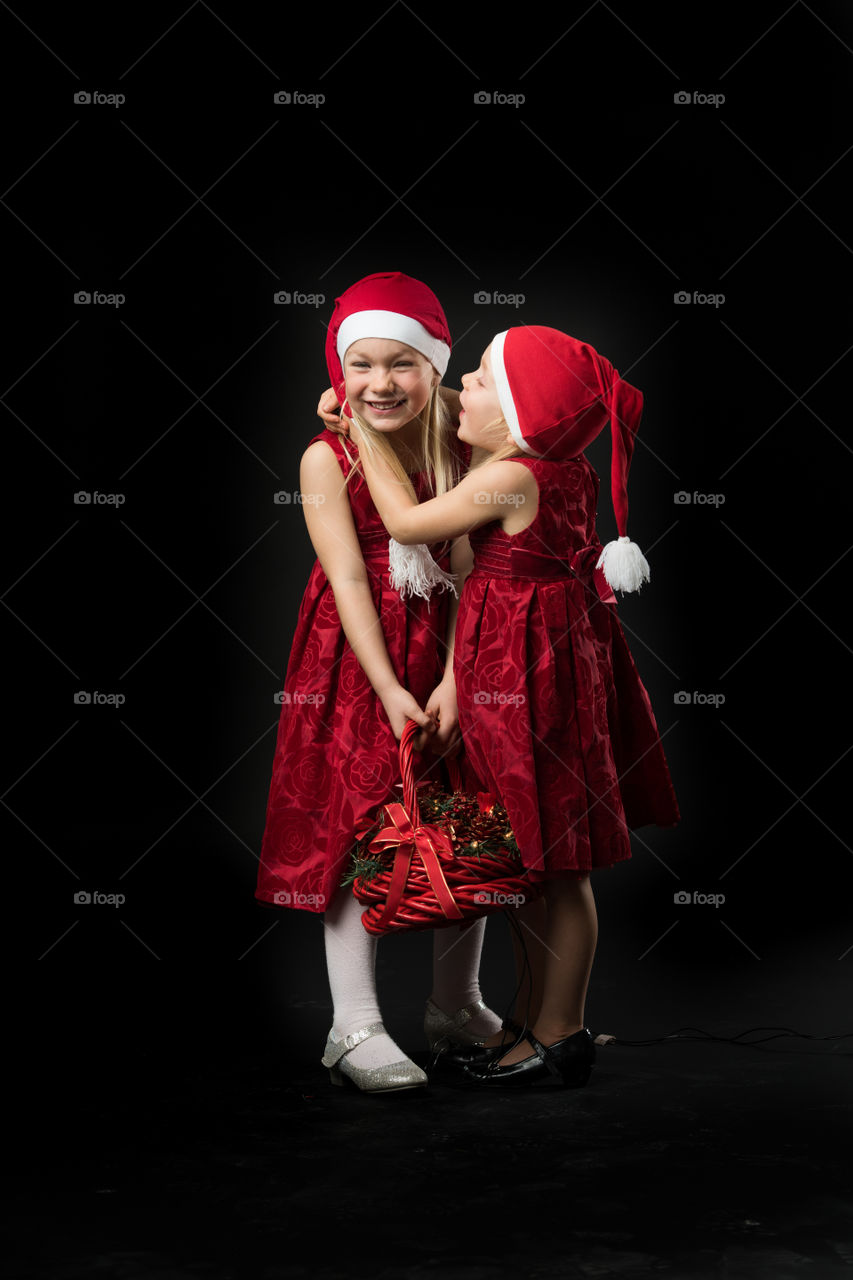 Two sisters dressed for christmas kissing.