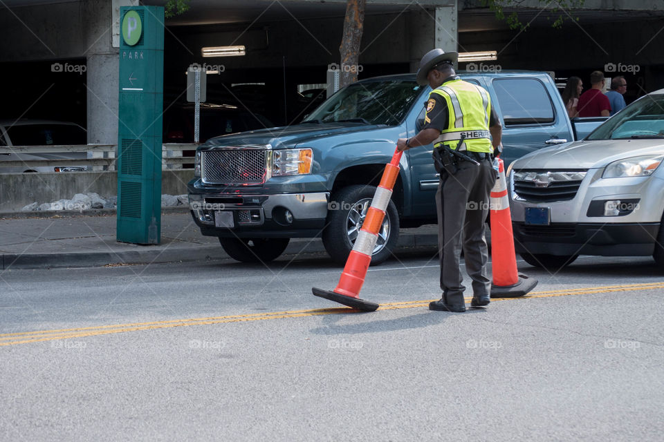 Police officer standing in an urban street and placing cones to direct traffic