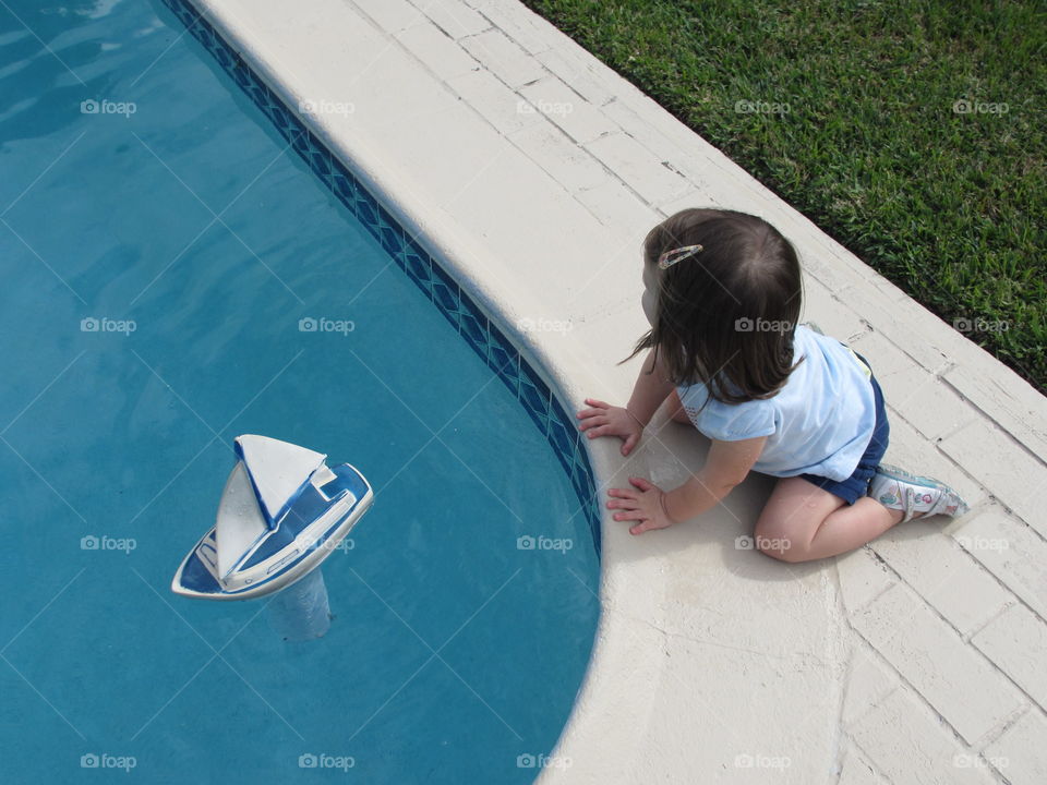 child & pool & sailboat. girl at play with sailboat