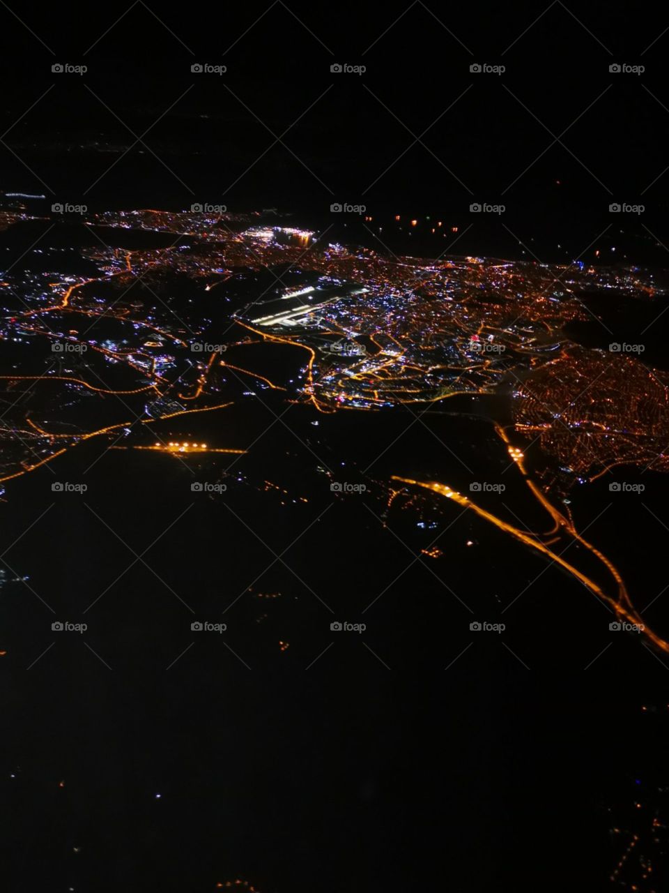 Iluminated with lights İstanbul city view from the airplane at night. Black colour on the ground is the sea.