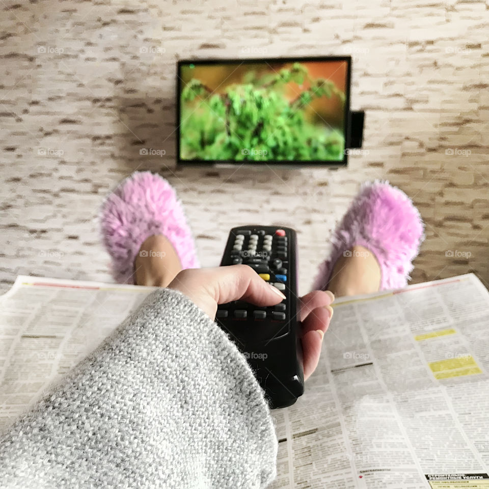 Watching television in warm sweater and cozy warm home slippers 