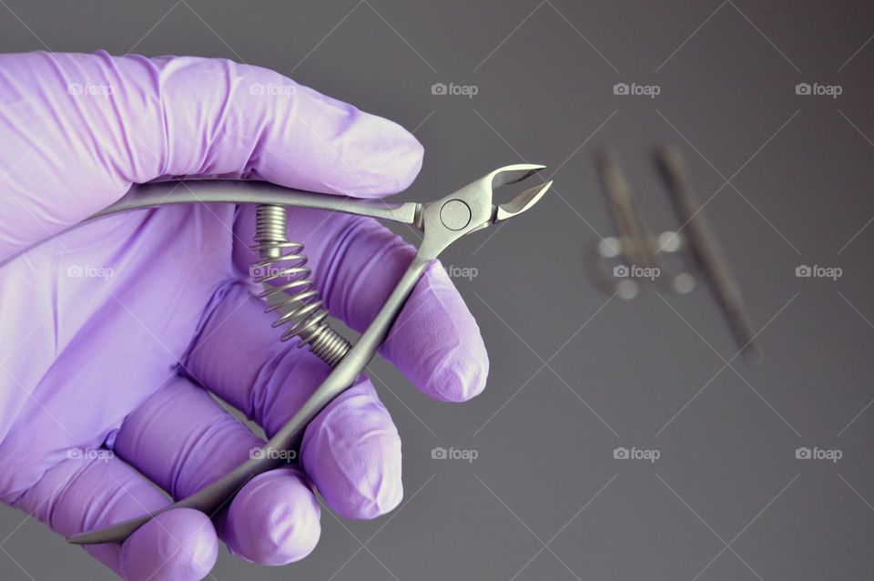 Manicure tools are held by a manicurist in rubber gloves