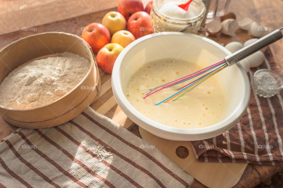 Making an apple pie dough using eggs, flour, sugar and apples.