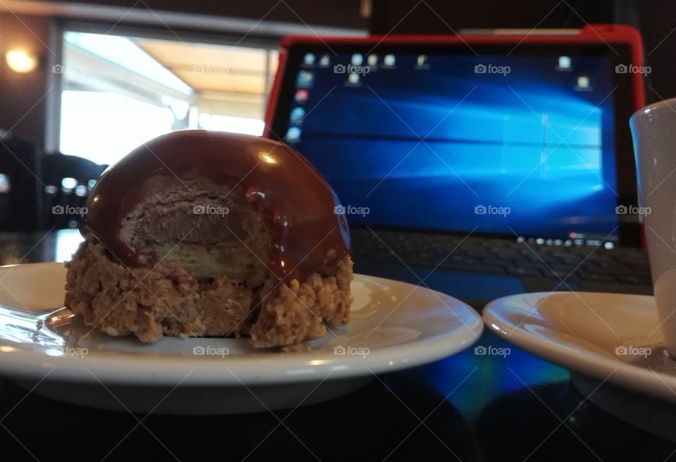 enjoying a coffee and a sweet while working on surface tablet