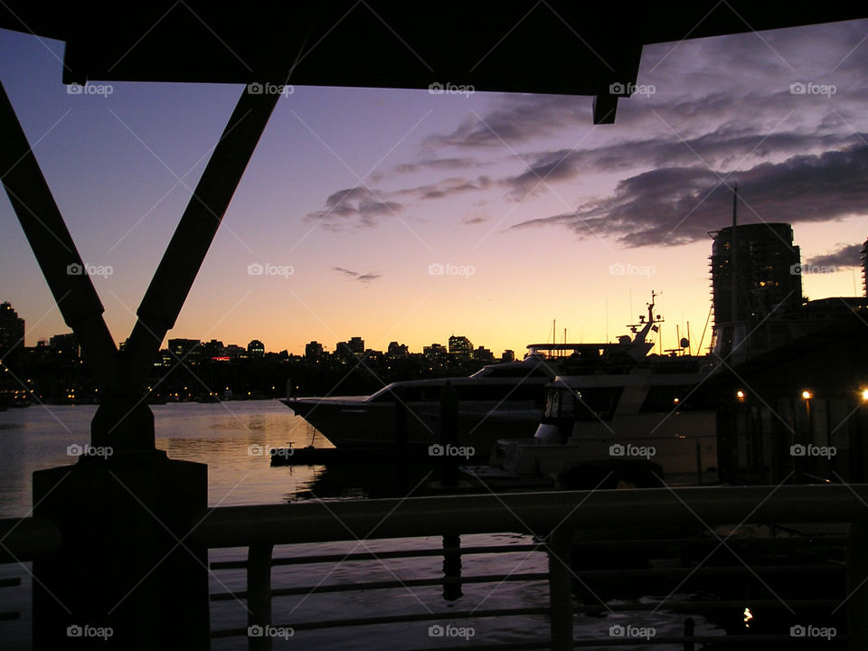 Morning or evening time - with silhouette of the buildings - water - yatch - sitting area - clouds.