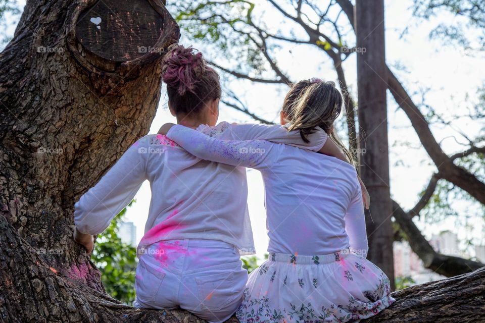 Two girls sitting on the tree