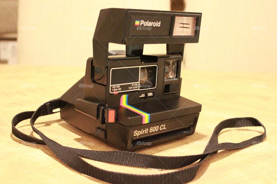 vintage black Polaroid camera sitting on wooden table, picture taken at an angle