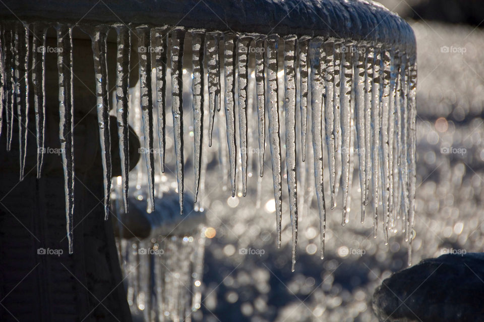 Icicles form on the edge of the picnic table backlit by the morning