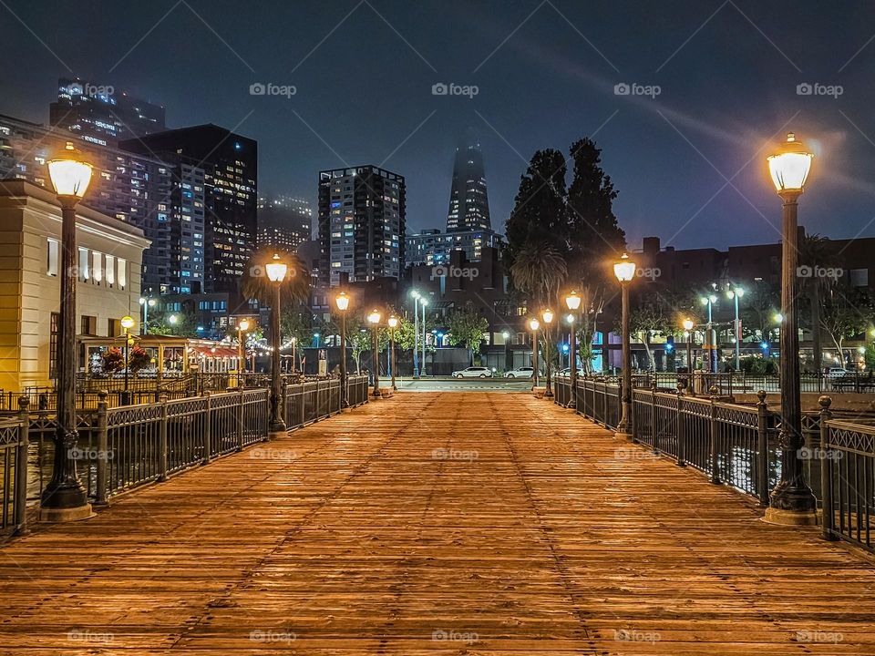 Night view of San Francisco looking down pier 7 on the waterfront with a slight bit of fog 