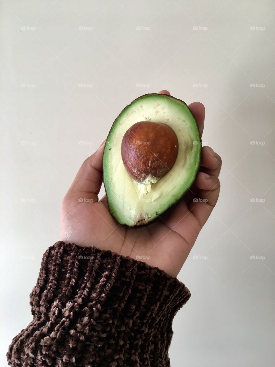 Person holding half avocado