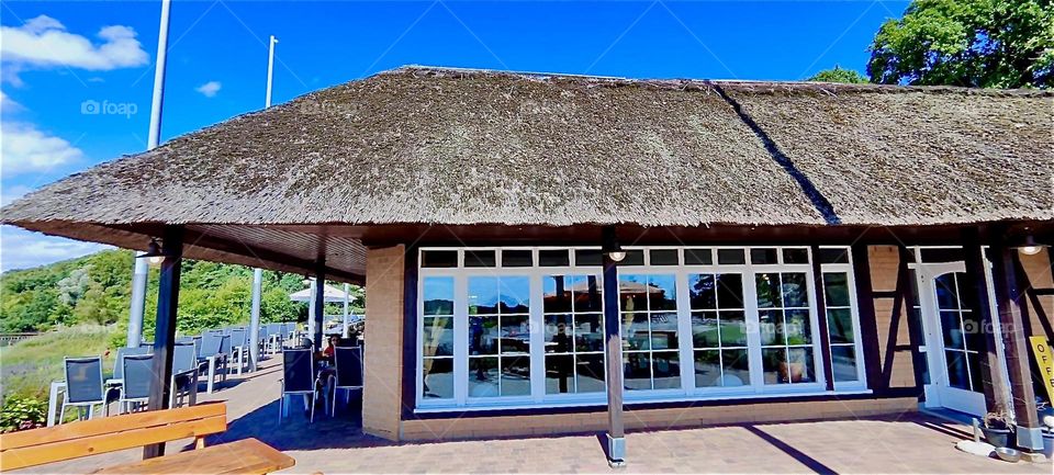 This inn at the “Strelasund”, a part of the “Baltic Sea” in “Mecklenburg - Western Pomerania”, Germany is built in the style of a fisherman’s hut, albeit much bigger. The nearby “Rügenbrücke” leads to the island of “Rügen”. 2024. Hypnotic Productions